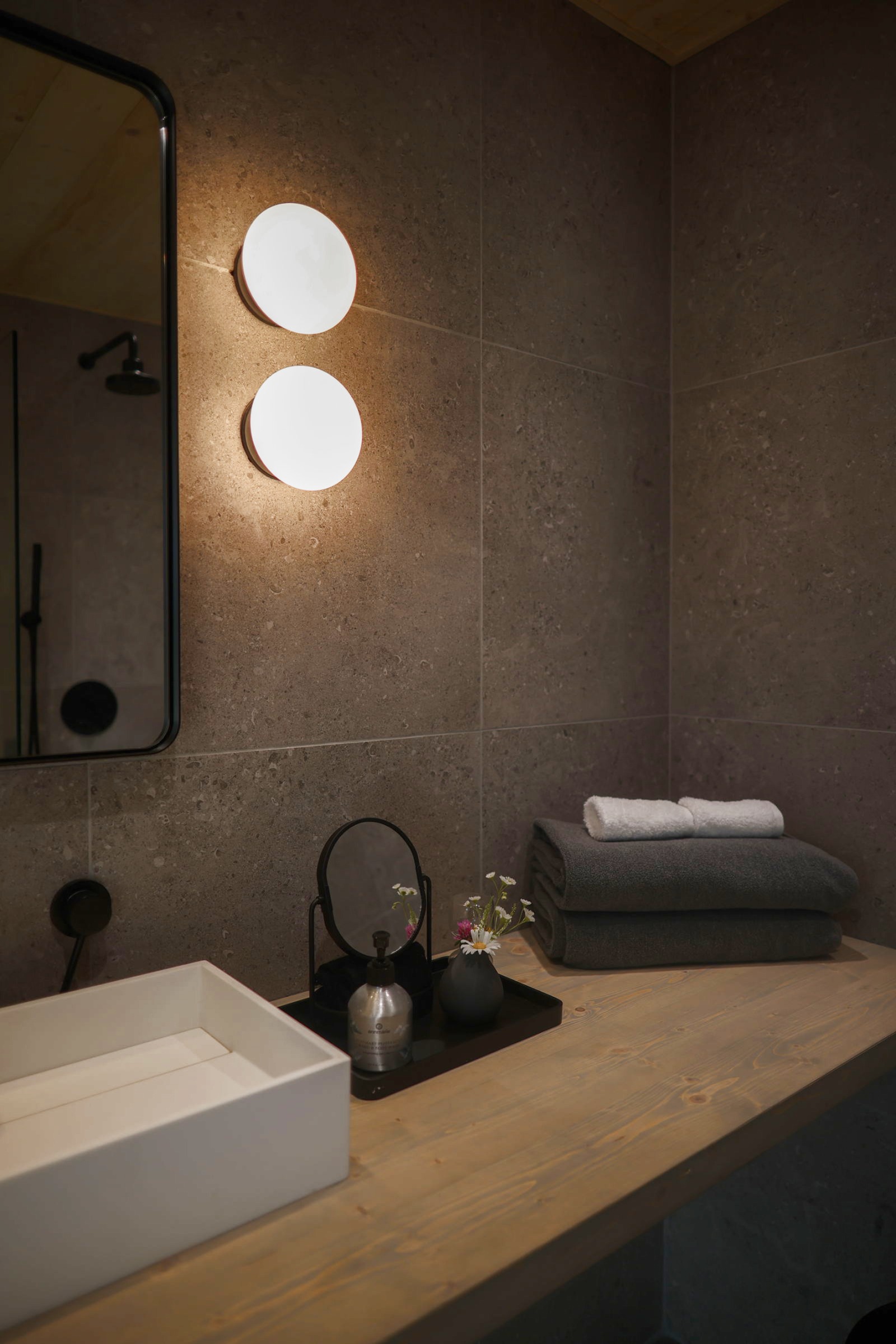 Bathroom with stone wall and warm sconces