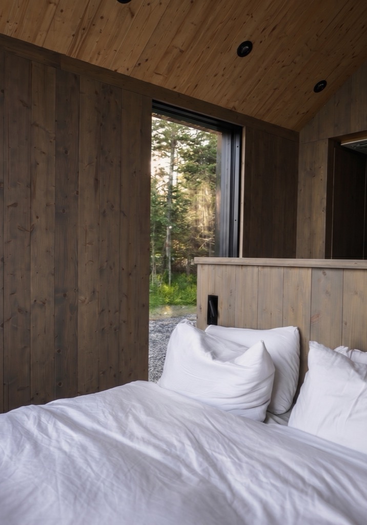 Timber hallway opening onto a window over the forest