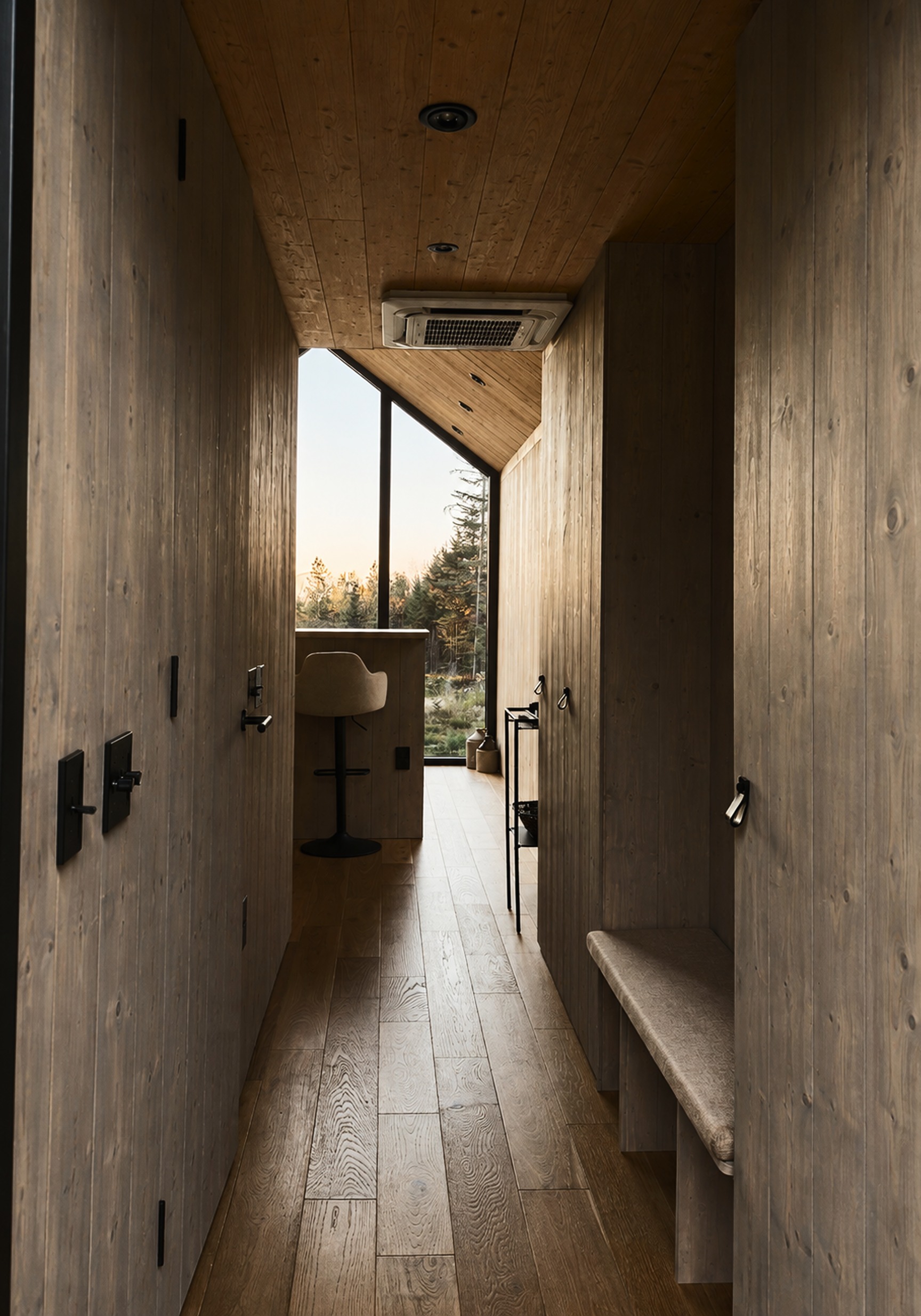 Bed beneath a pitched timber ceiling, forest through the window